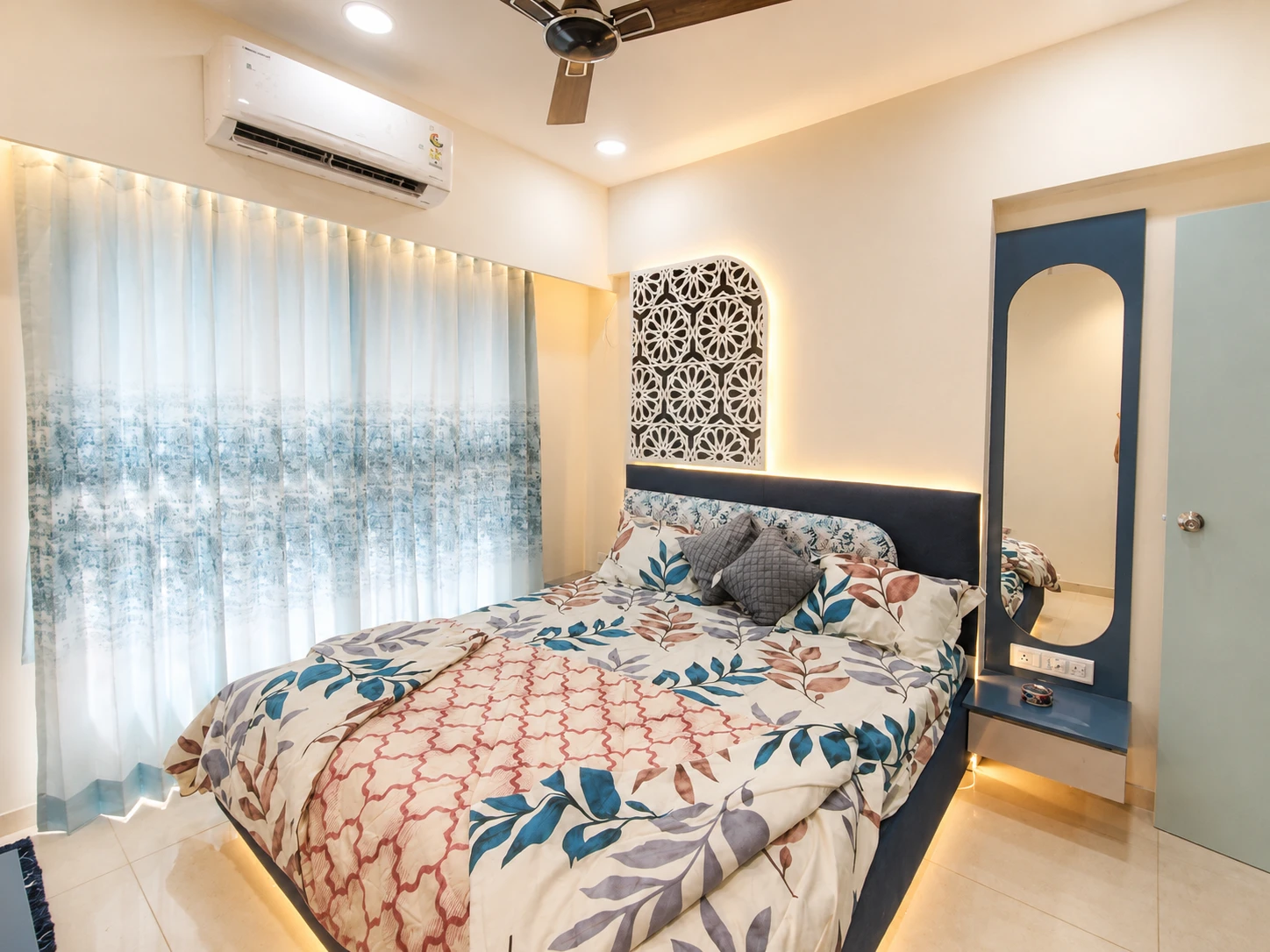 A bedroom detail with grey panelling, warm lights and curtains that gel well with the rest of the design.